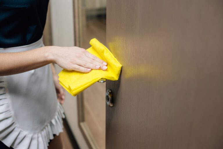 cropped shot of maid in uniform cleaning hotel suit with rag