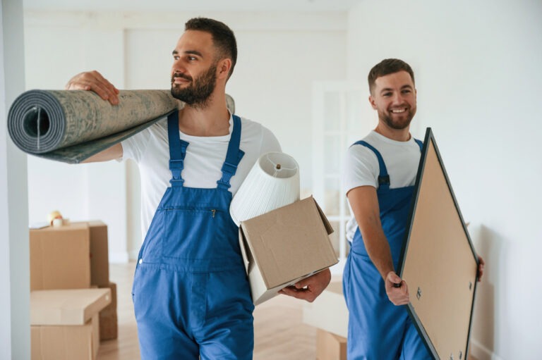 Mat and painting in hands. Two moving service employees in a room.